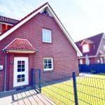 Rotes Backsteingebäude mit weißer Tür und gepflegtem Garten.