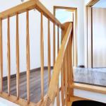 Holzgeländer und Treppenhaus mit Holzfußboden und weißen Wänden.