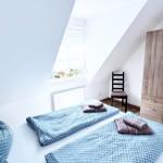 Schlafzimmer mit Dachschrägen, Bett, Kleiderschrank und Fenster.