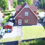 Rotes Backsteingebäude mit Vorgarten und Garage. Gartenhaus und Müllcontainer sind sichtbar.