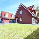 Rotes Backsteingebäude mit Garten, Terrasse und Sonnenschirm.