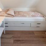 Schlafzimmer mit Doppelbett, Schubladen und Nachttisch unter Dachschräge