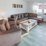 Wohnzimmer mit braunem Sofa, Holztisch und Bücherregal.