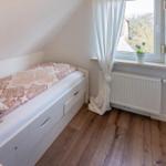 Schlafzimmer mit Dachschrägen, Bett, Fenster und Heizkörper.