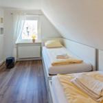 Zwei Betten mit gelben Bettwäsche, Holzboden und Fenster mit Vorhang.