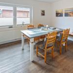 Esszimmer mit Holztisch, Stühlen und Fenster. Wandbildern und Bank.