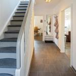 Hausgang mit Treppe und Blick in Wohn- und Essbereich.