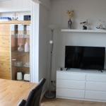 Living room with TV, cabinet, and floor lamp. Decor includes sailboat and lighthouse.