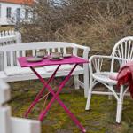 Outdoor area with white sofa, chair, and pink table. Two cups are on the table.