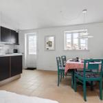 Kitchen with dining area, table with red-and-white checkered cloth and green chairs.