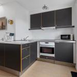 Kitchen with dark cabinets, stainless steel countertop, and built-in oven.