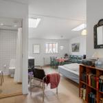 Bedroom with bed, bookcase, and view into bathroom.
