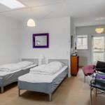 Two single beds, a mirror, and a window with view outside.