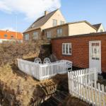 Red brick building with white door and fence. Outdoor area with chairs.