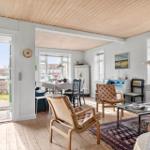 Living and dining area with wooden floor, windows, and chairs.
