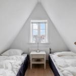 Two beds under sloped ceilings with window and nightstand.