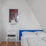 Bedroom with blue headboard, white nightstand, and cat picture on the wall.
