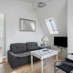 Living room with sofa, table, and TV. Skylight and mirror on the wall.