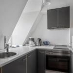 Kitchen with range hood, sink, stove, and microwave under sloped ceiling.