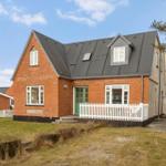 A red brick house with a green door and white fence.