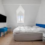 Bedroom with bed, window, and TV. Blue dresser and chair.