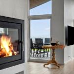 Living room with fireplace, TV, and view of terrace and sea.
