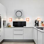 Modern kitchen with white cabinets, stainless steel appliances, and red wall lights.