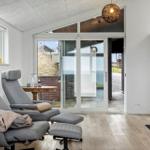 Two gray recliners with footstools stand before a glass door. A fireplace is mounted on the wall.