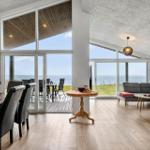 Large living and dining room with sea view through large windows and terrace.