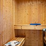 Wooden sauna with bench and blue towel.