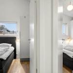 Two bedrooms with beds, windows, and white wardrobes. Wooden floor and ceiling light.