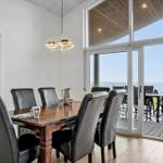 Dining room with table and chairs. Large glass doors lead to terrace with sea view.