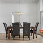 Dining room with wooden table, black chairs, and large window. Floor is wood.