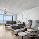 Living room with sea view, sofa, and two chairs.
