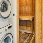 Dryer and washing machine next to a wooden sauna with bench.