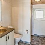 Bathroom with sink, toilet, and shower. Wall with plant and window.