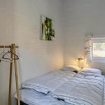 Bedroom with double bed, coat rack, and window with curtains.