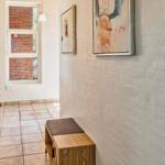 Hallway with wooden bench, wall art, and view into bedroom with bed.