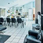 Living and dining area with kitchen, black leather chairs, and white tiled floor.