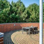 Terrace with table and chairs, surrounded by red bricks and trees.