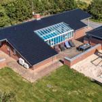 Modern holiday home with pool, playground, and grill area in green surroundings.