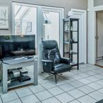 Living room with fireplace, TV, and leather armchair. Door leads to bedroom.