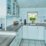 Kitchen with white cabinets, wooden countertops, and window with plant.