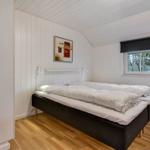 Bedroom with double bed, wooden floor, and window with view of trees.
