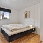 Bedroom with bed, window, and wooden floor.