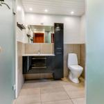Bathroom with shower, sink, and toilet. Wooden handle on shower door.