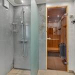 Shower with rain showerhead and sauna in background