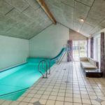 Indirectly lit indoor pool with slide and seating area.