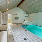 Indoor pool and hot tub with window and bench.