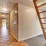 Hallway with wooden wall and ladder to upper level. Terrace with garden furniture visible.